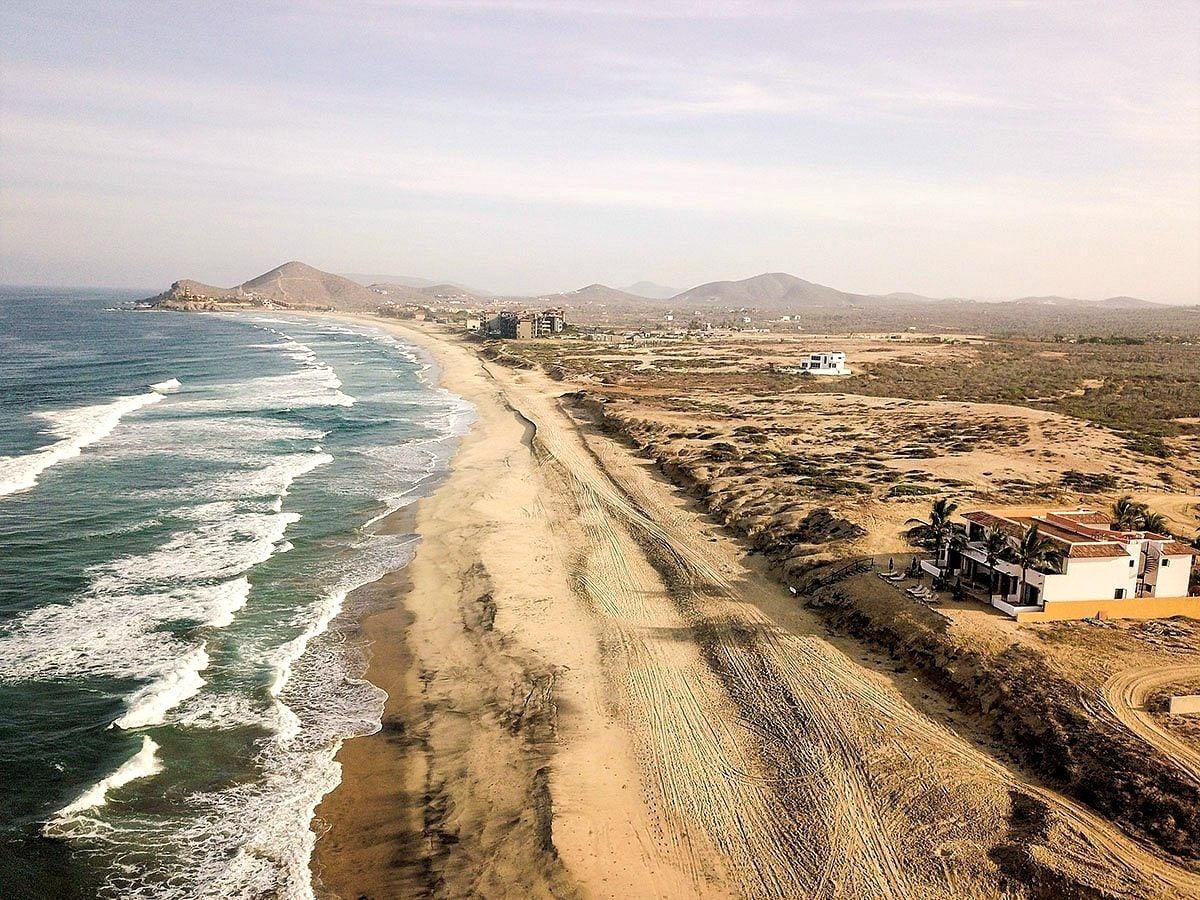 The coastline at El Pescadero seen from the air, white surf tracing miles of empty beach