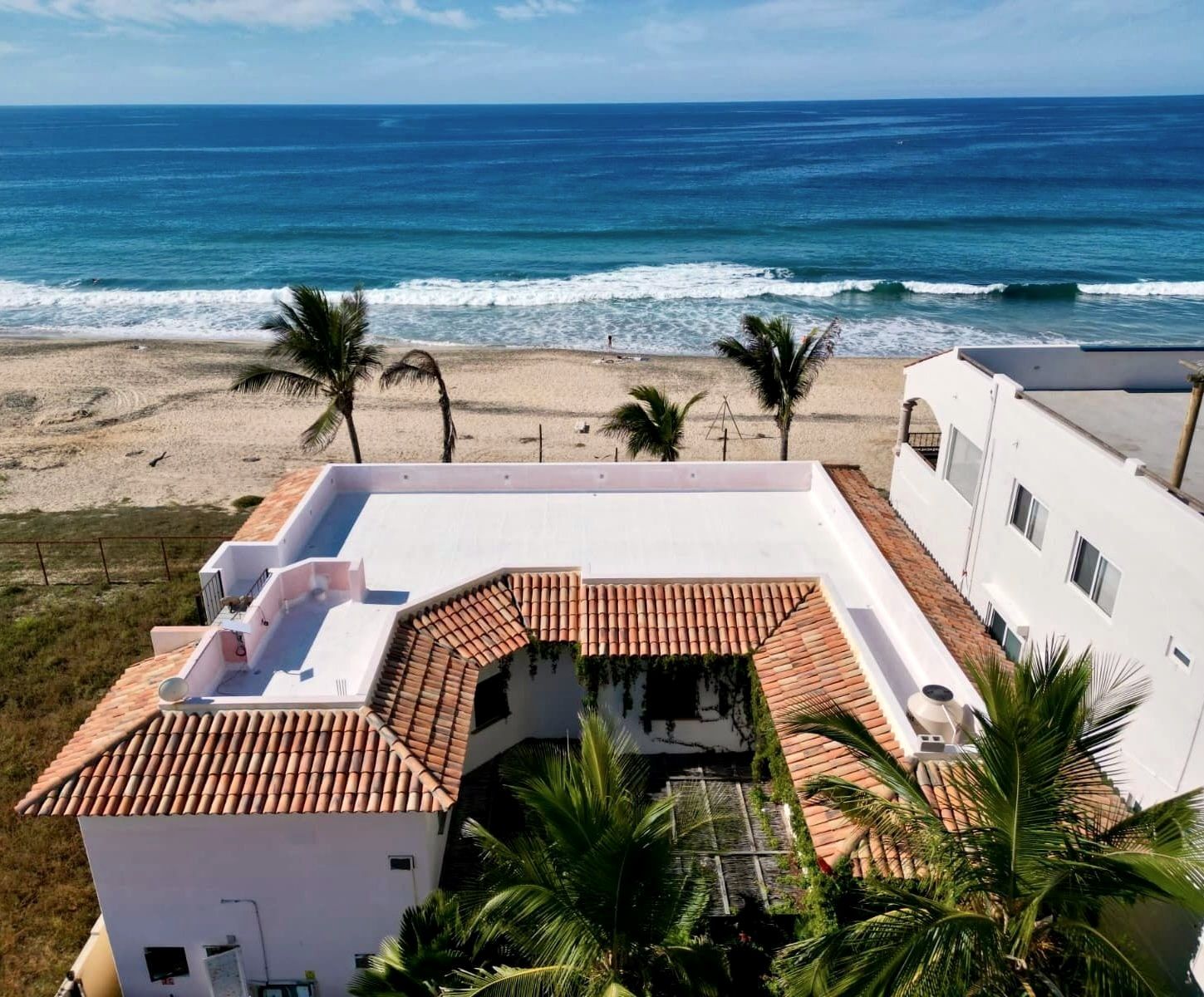 The rooftops of the inn from above, with the Pacific breaking along the shoreline beyond
