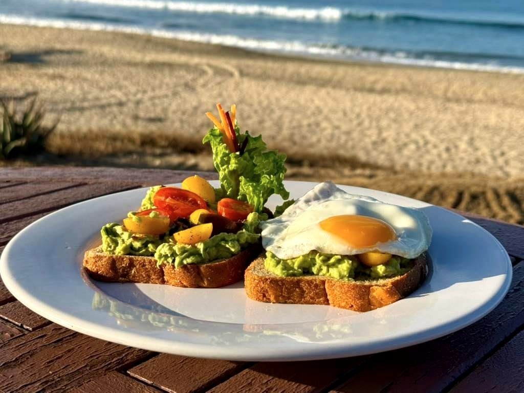 Avocado toast topped with a fried egg and fresh tomato