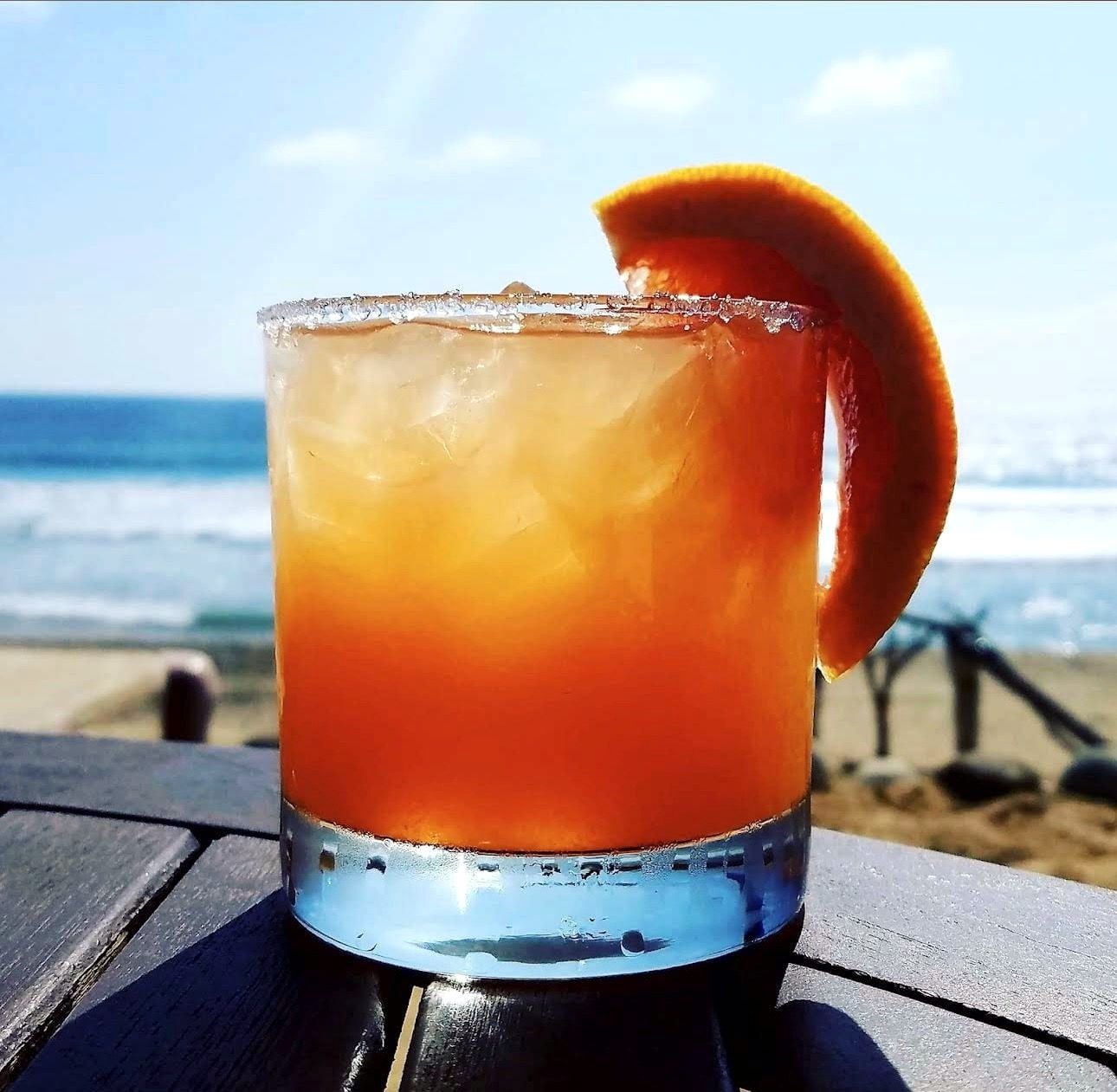 A house cocktail with a salted rim, the ocean out of focus behind it