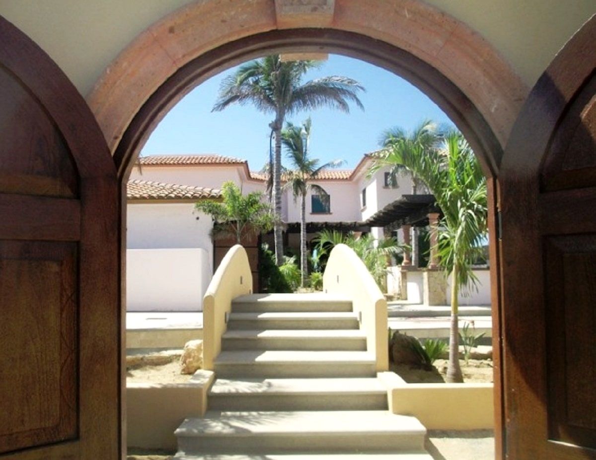 Stone steps rising through a whitewashed archway into the hotel gardens