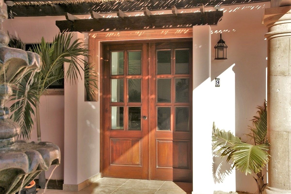 Carved wooden double doors at a guest room entrance, framed by tropical planting