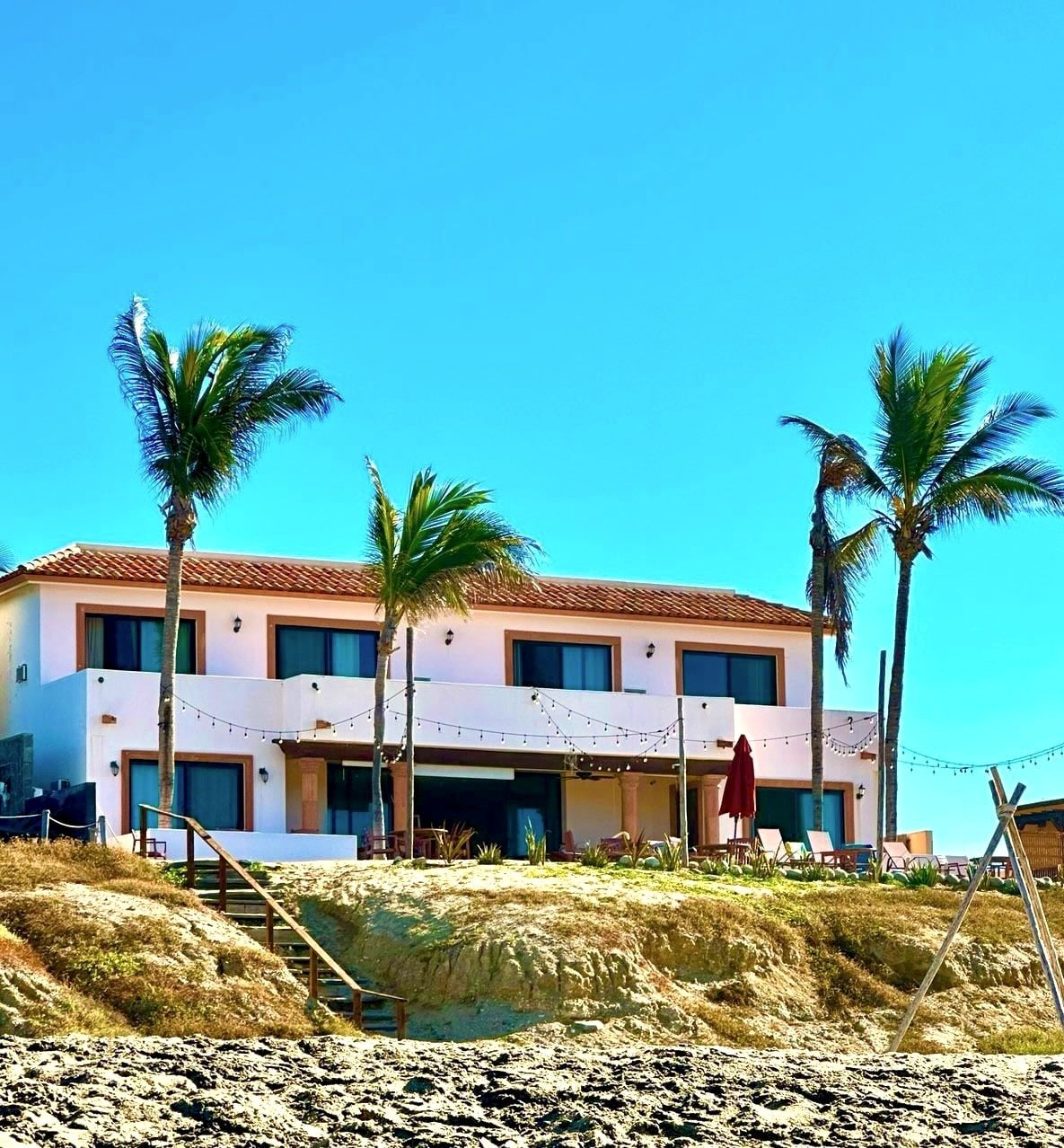 The white-and-terracotta guest wing of the inn behind tall palms