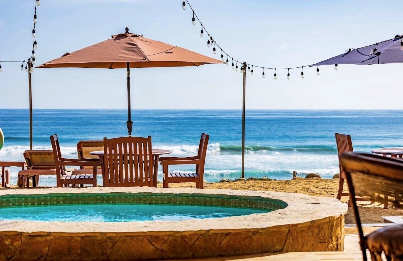 Sun umbrella and wooden chairs beside the pool, the Pacific directly behind