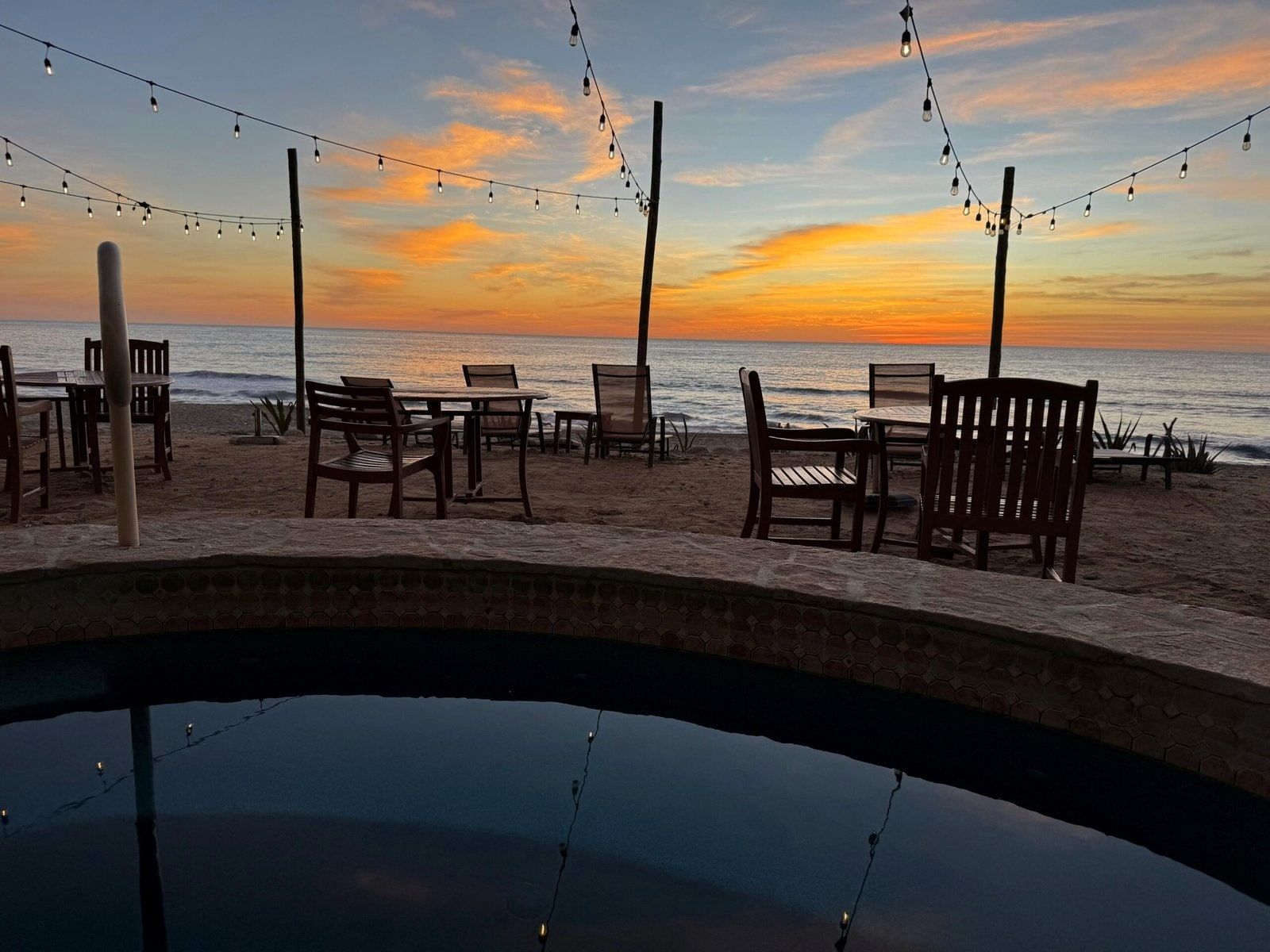 Chairs and string lights on the rooftop terrace as the sun sets over the ocean