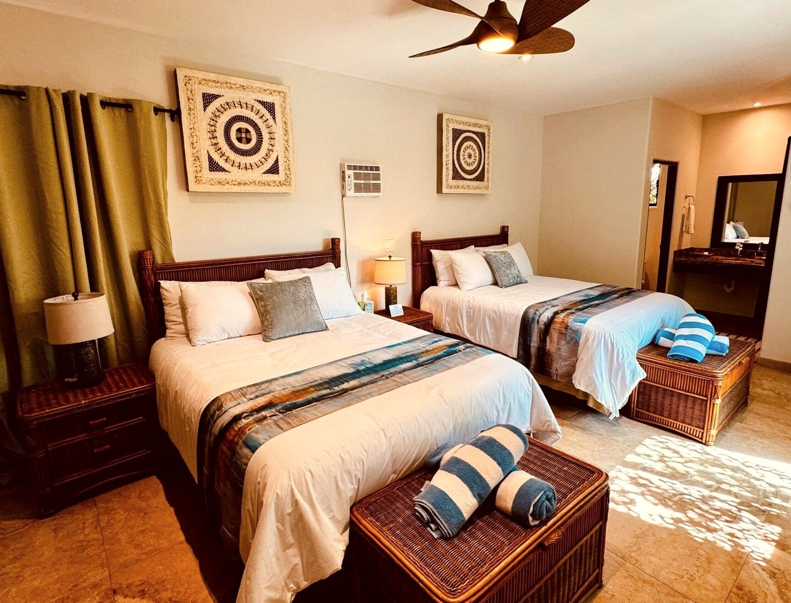 A room with two queen beds, woven furniture and framed local artwork