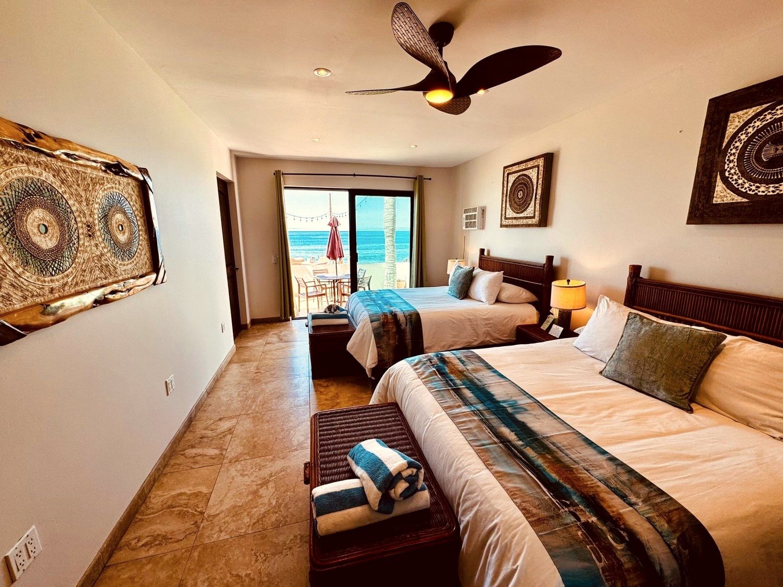 An oceanfront room with two queen beds opening onto a private balcony above the sand