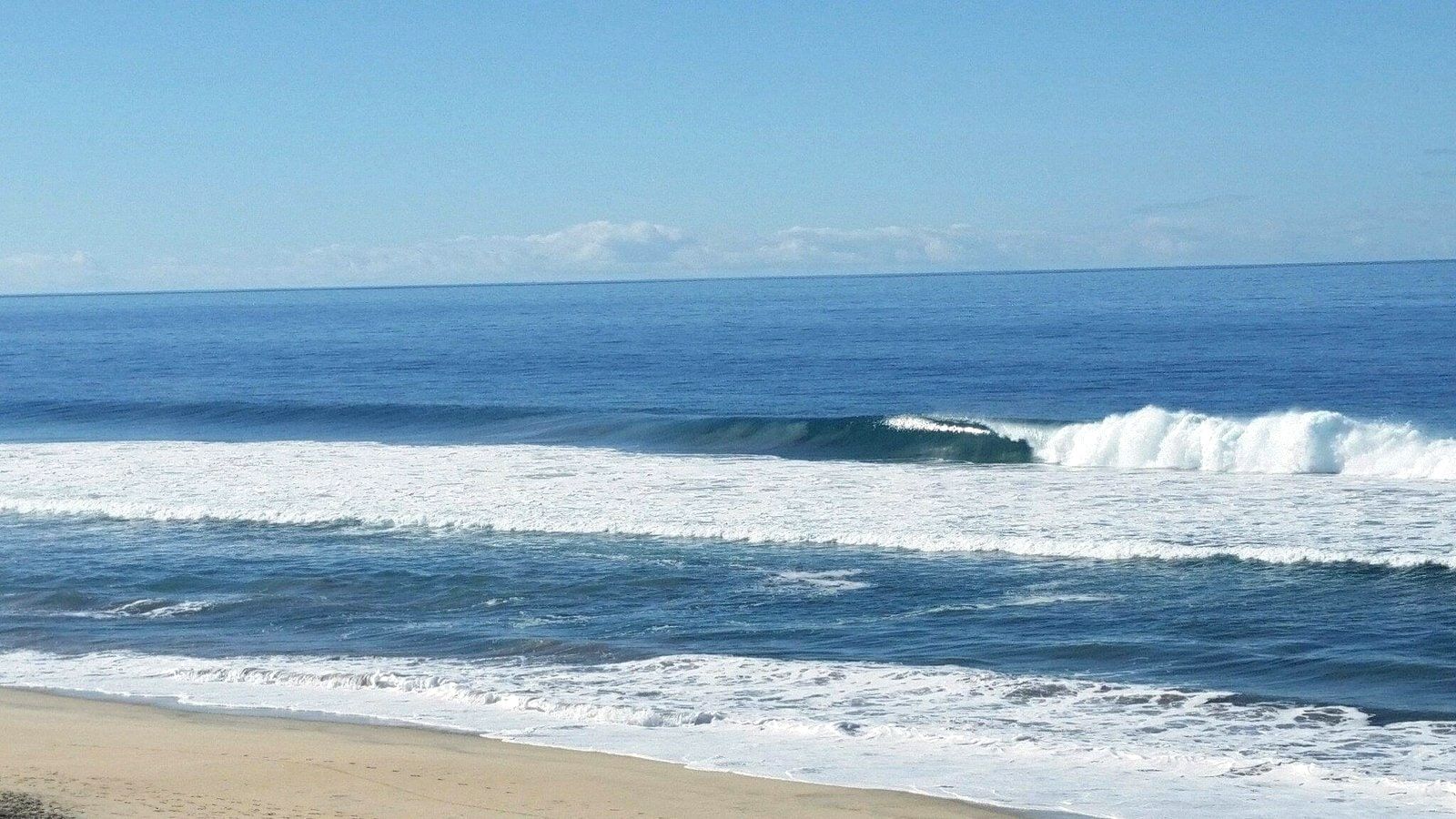 A clean right-hand wave breaking along the beach at Cerritos